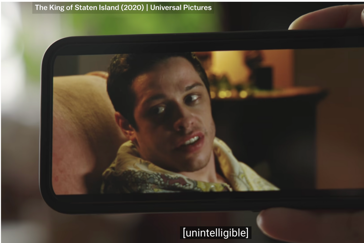 someone watching a video of Pete Davidson on their phone with subtitles at the bottom