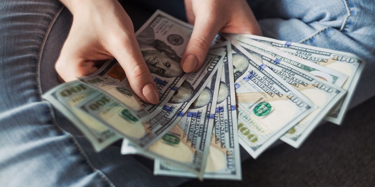 Woman holding many U.S. $100 bills