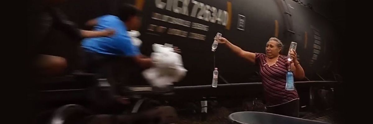 woman hands food to men hanging from a train that is bound for northern Mexico