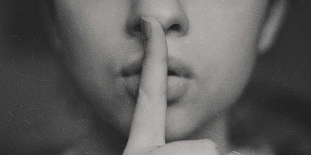 Woman keeping secret by holding finger to lips and whispering, "Shhh"
