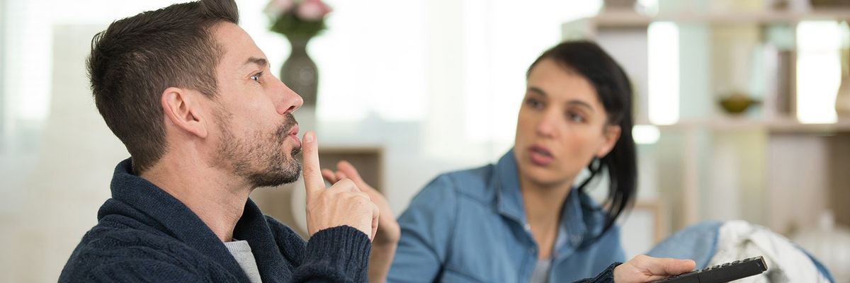 a man telling a woman to be quiet while he watches tv