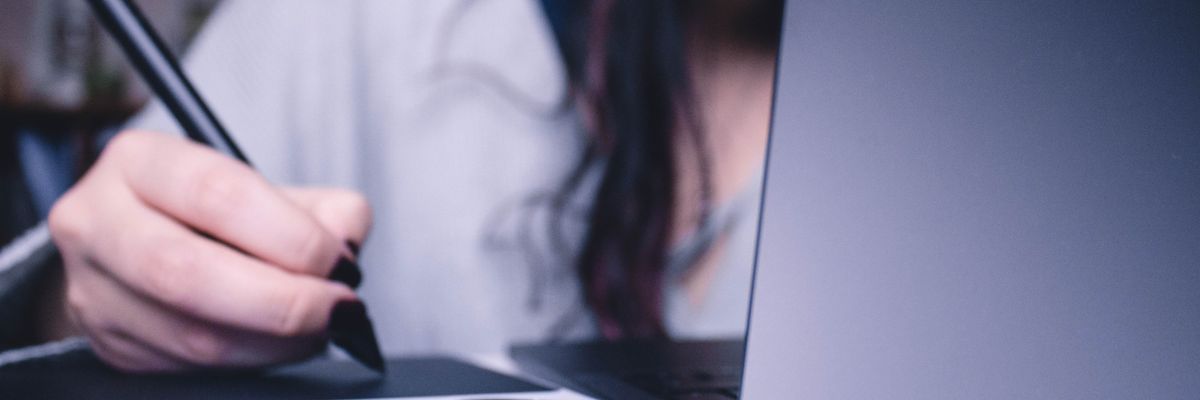 woman using drawing pad while sitting in front of laptop