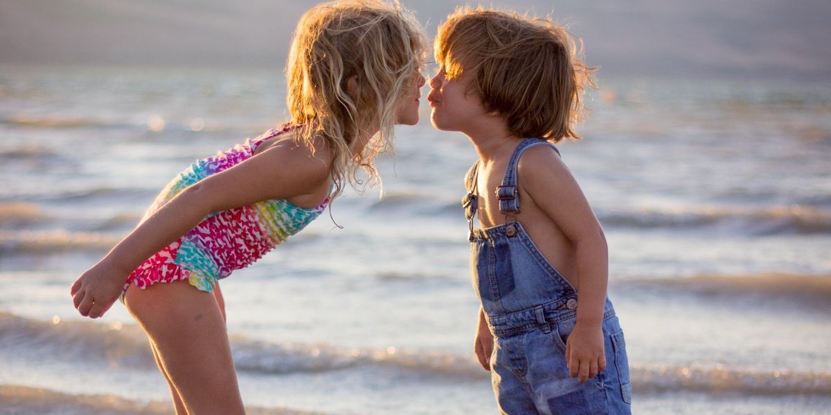 girl and boy kissing on beach during daytime