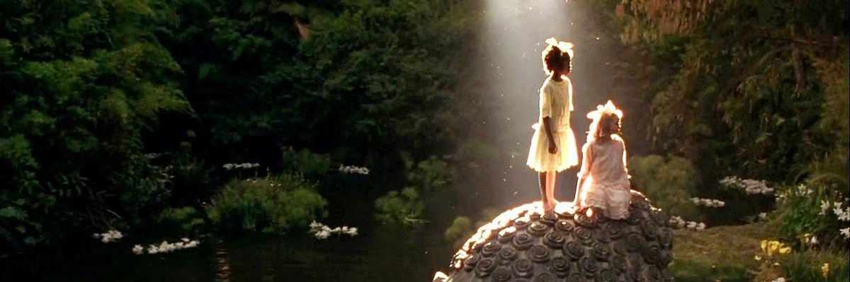 Still image from the film A Little Princess / La Princesita (1995) directed by Alfonso Cuar\u00f3n showing two little girls on top of an abandoned buddha statue being illuminated by a ray of sunshine