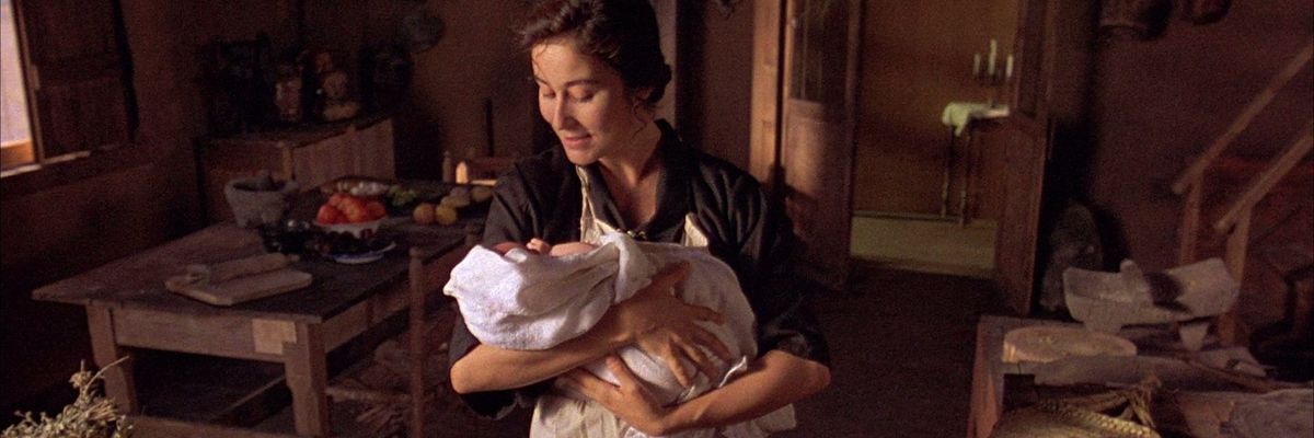 Still image from the film Like Water for Chocolate / Como Agua Para Chocolate (1992) directed by Alfonso Arau showing a woman in a kitchen holding a newborn baby