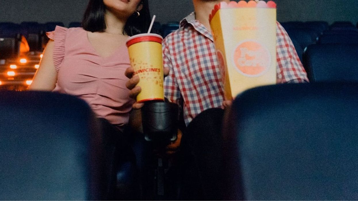 Couple sharing soda and popcorn in a theater