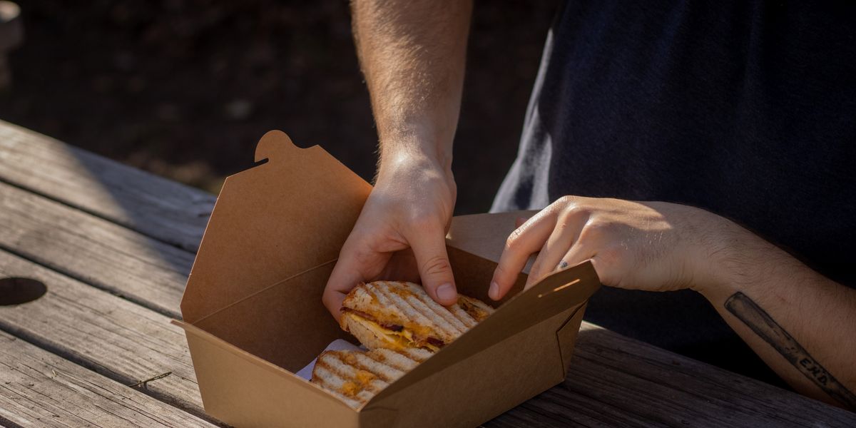 Man putting a sandwich in a to go box