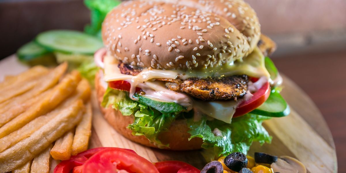 hamburger with vegetables and meat beside French fries