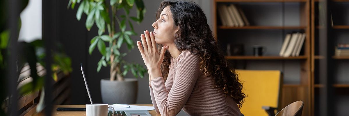 brown haired woman at a desk looking out the window