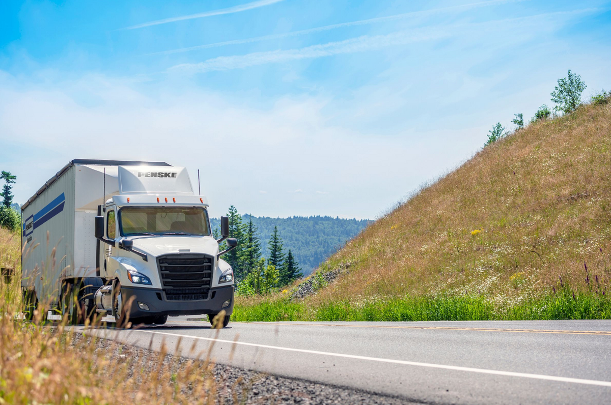 Image of Penske Logistics tractor-trailer driving in springtime scenery.