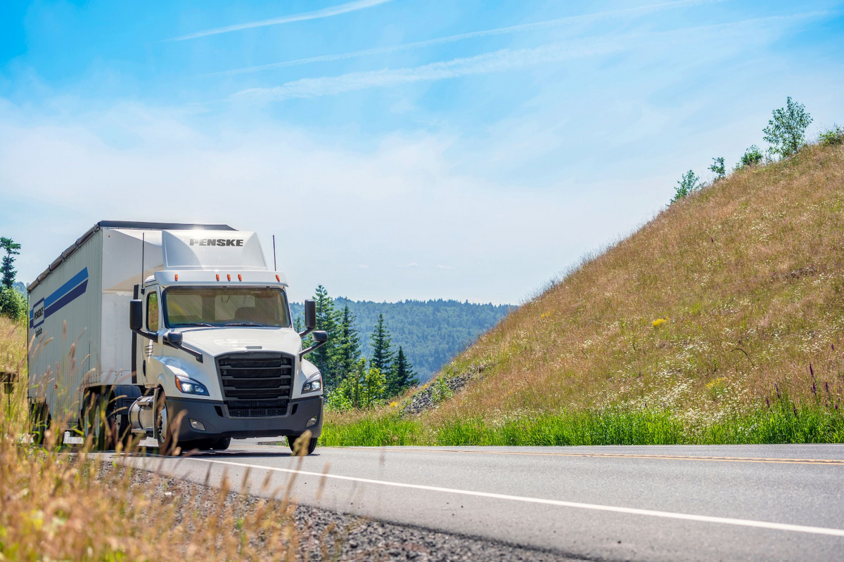 Image of Penske Logistics tractor-trailer driving in springtime scenery.