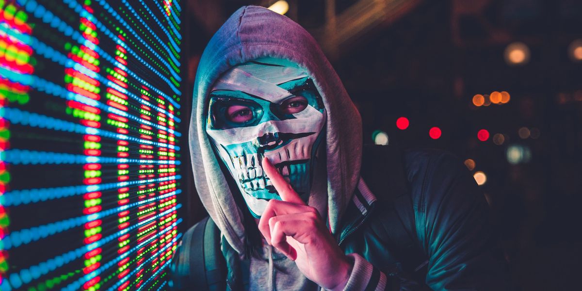 Person wearing a skull mask and shushing the camera