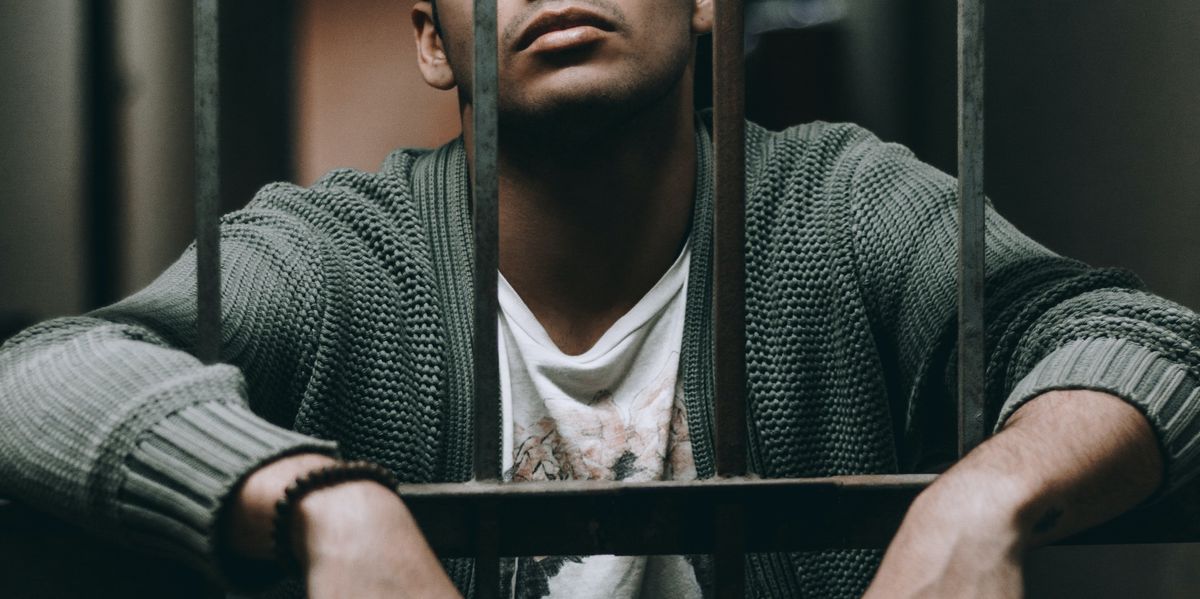 Man leaning forward into prison bars
