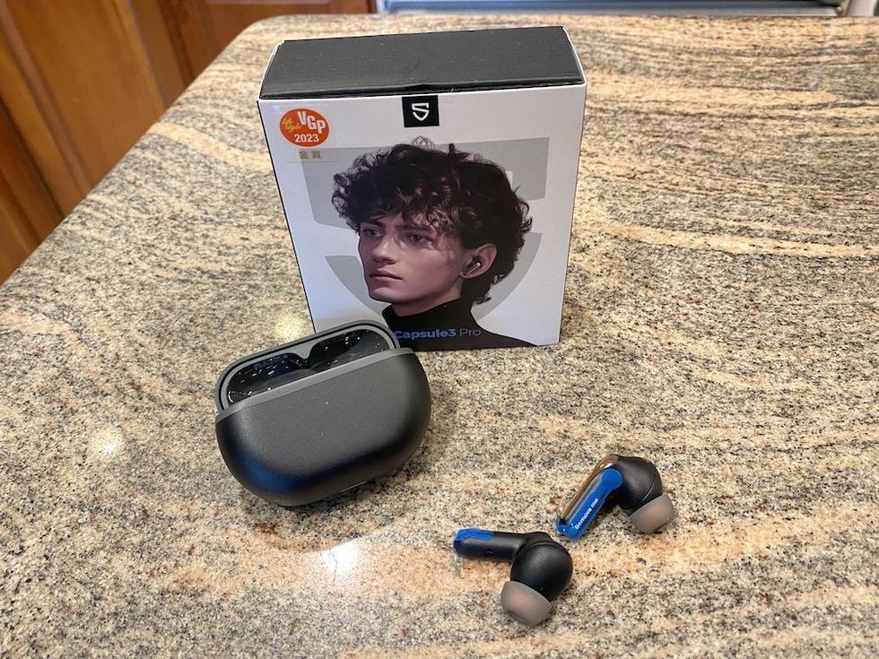 A photo of Soundpeats Capsule3 Pro Wireless Earbuds box, wireless charging case and earbuds on countertop