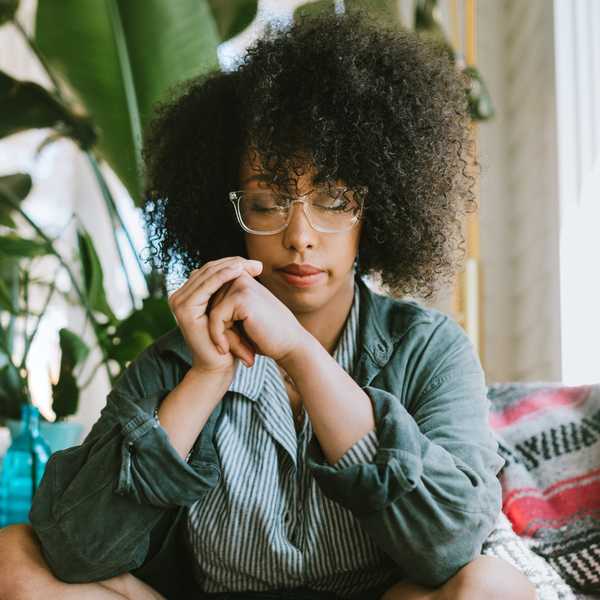 Woman-wearing-glasses-sitting-cross-legged-meditating-resting-her-eyes