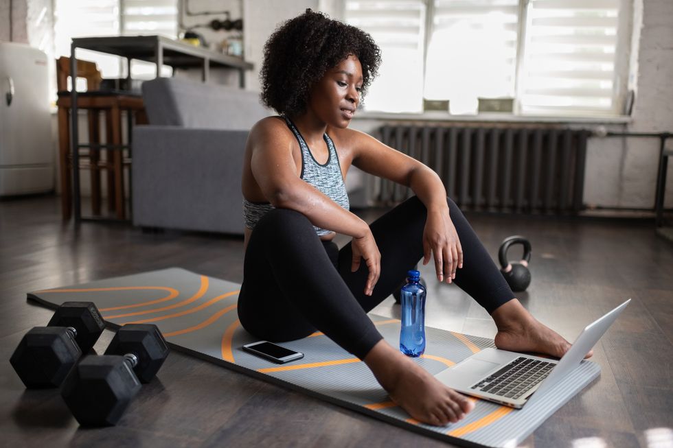 Sweaty-woman-sitting-on-yoga-mat-after-at-home-workout