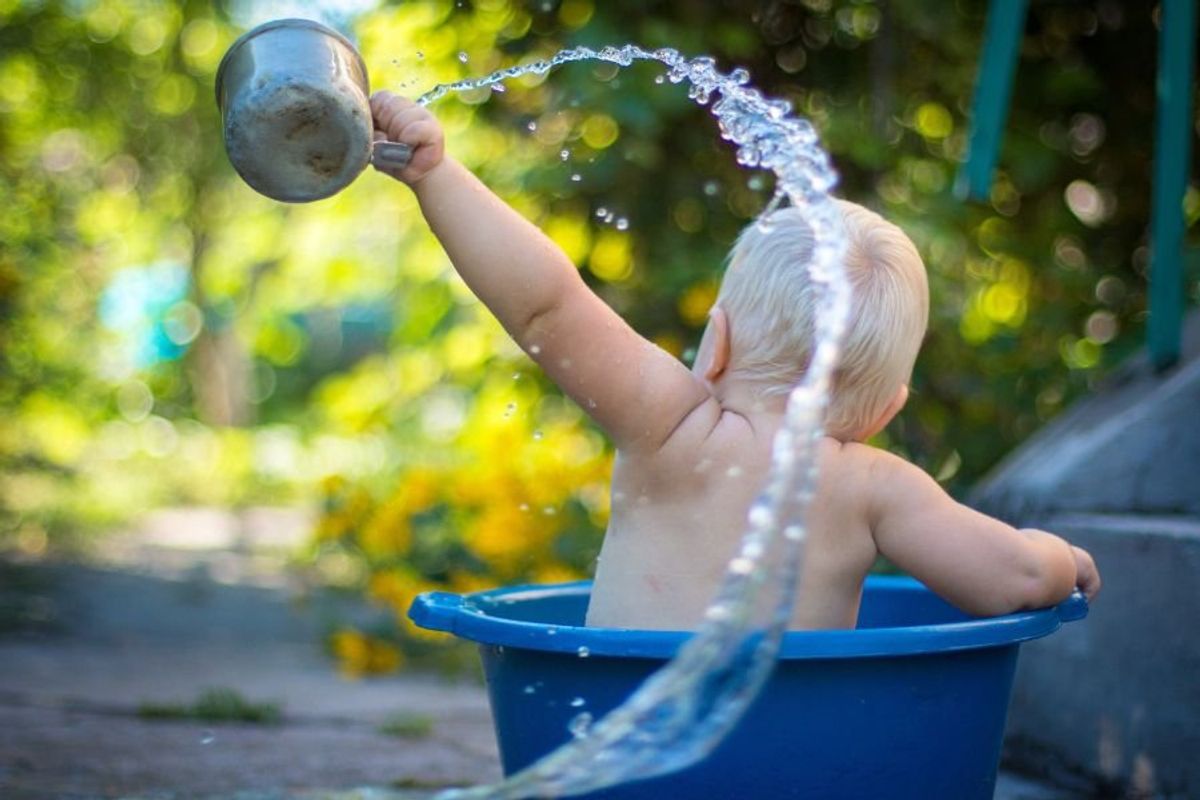 Baby splashing in bucket outside