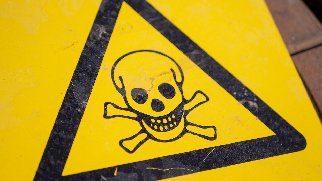 A yellow and black hazard warning sign with a skeleton head