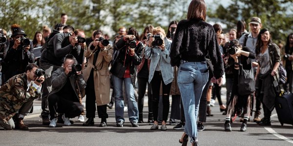 A well dressed woman walks towards the paparazzi