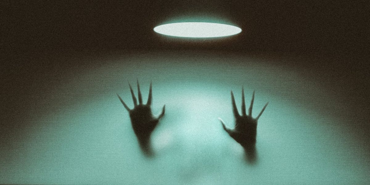 Two creepy, non-human hands come out of a mist and lay against glass