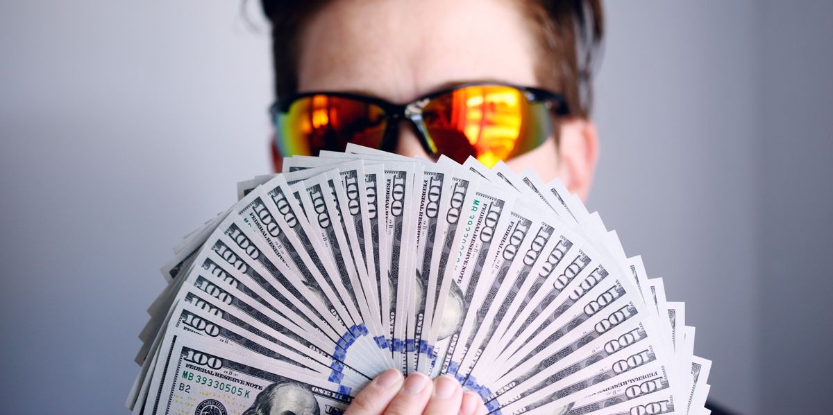 Man with expensive glasses and money fanned out in front of his face