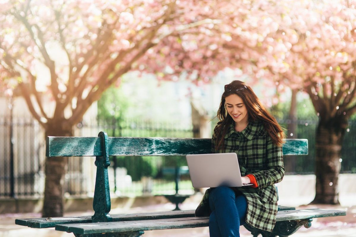 a photo of woman outside shopping on a laptop