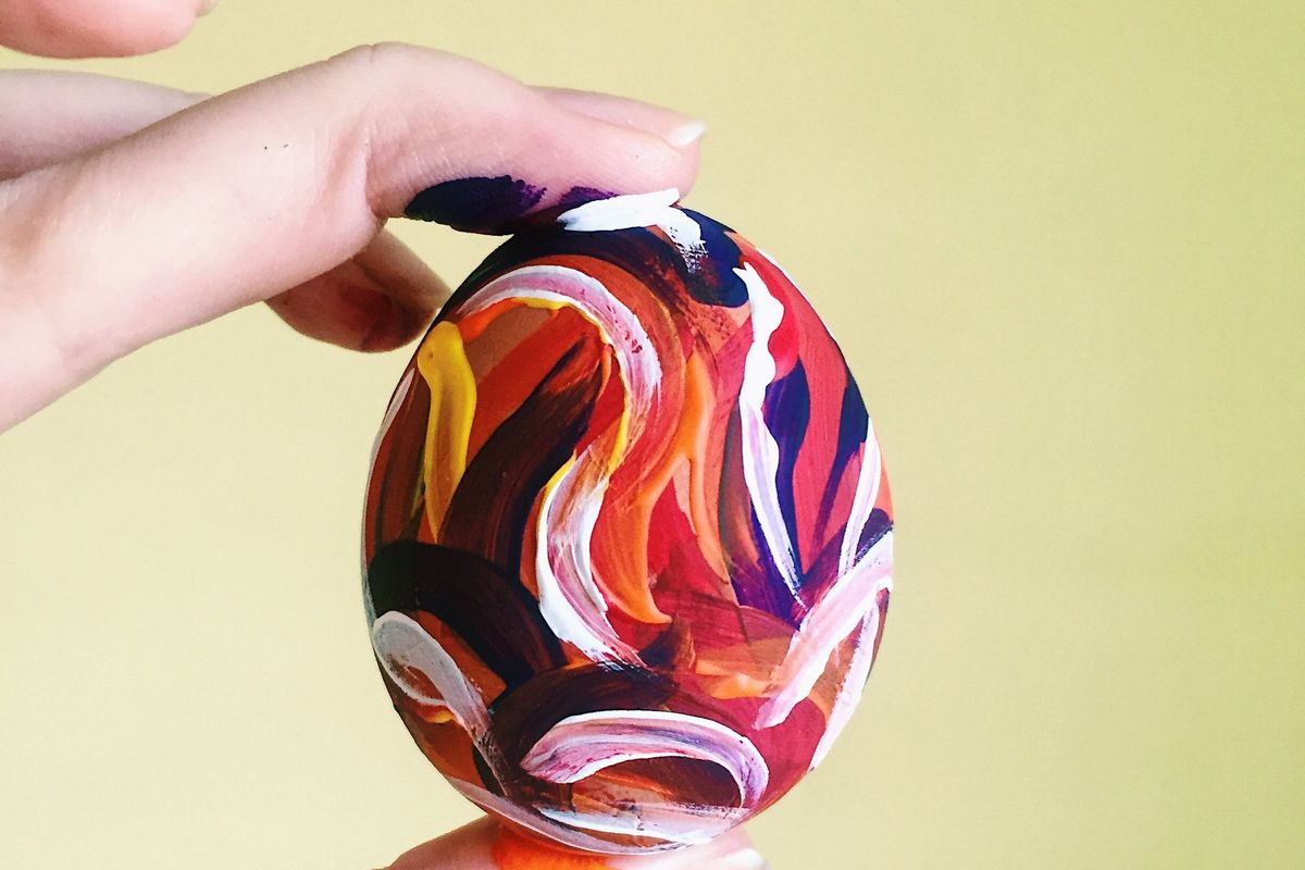 person holding a brightly painted egg