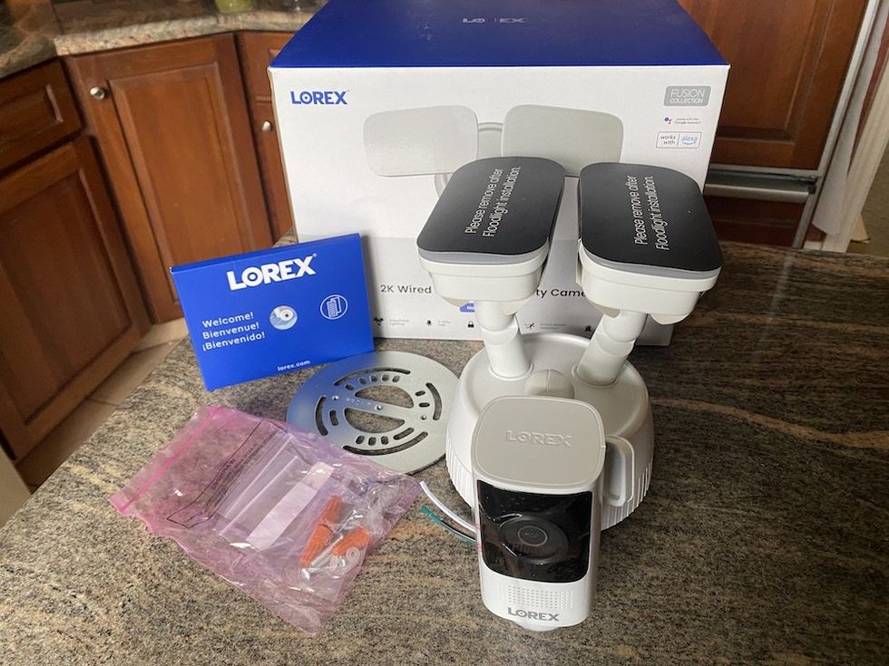 a photo of Lorex 2K Wired Floodlight Security Camera unboxed on a countertop