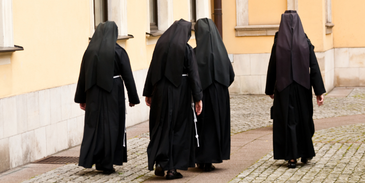 nuns walking down a cobblestone street