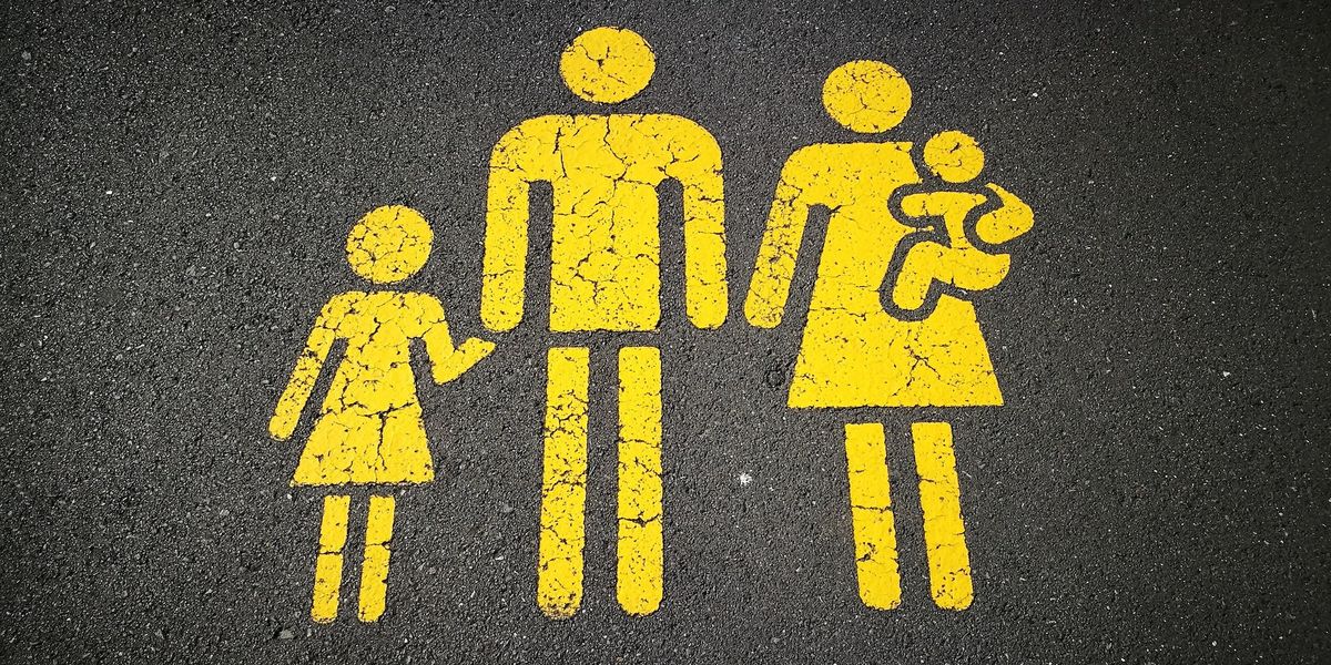 A yellow stick figure family painting (little girl, dad,  mom, baby) on asphalt 