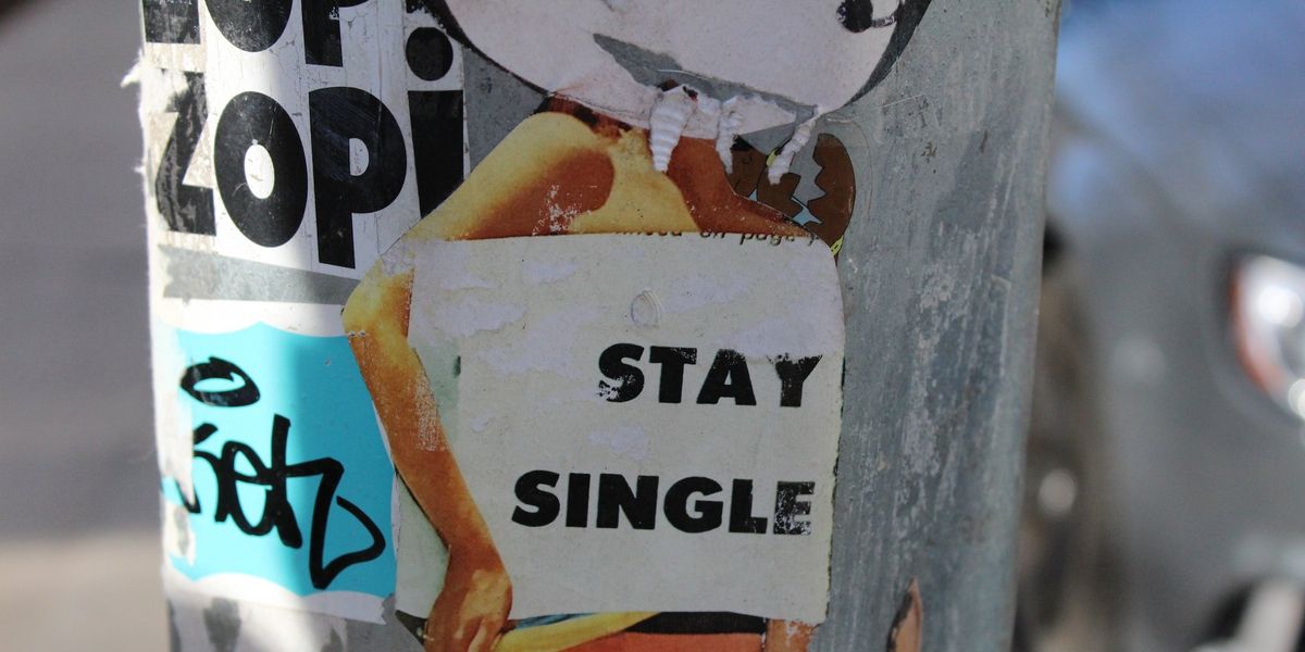 A artistic picture of a woman holding a sign saying, stay single