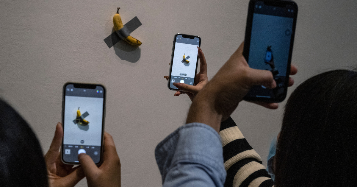Visitors take pictures of the work "Comedian" by Italian artist Maurizio Cattelan that is part of his exhibition "The Last Judgement'' at the UCCA Center for Contemporary Art