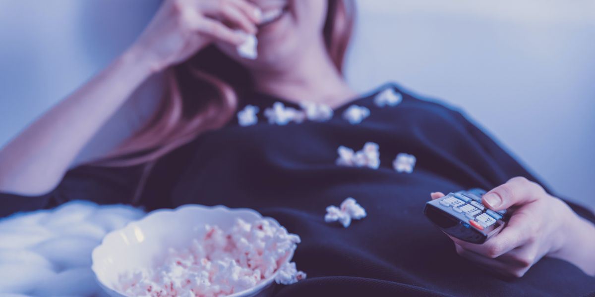 Woman laughing and covered in popcorn while watching TV