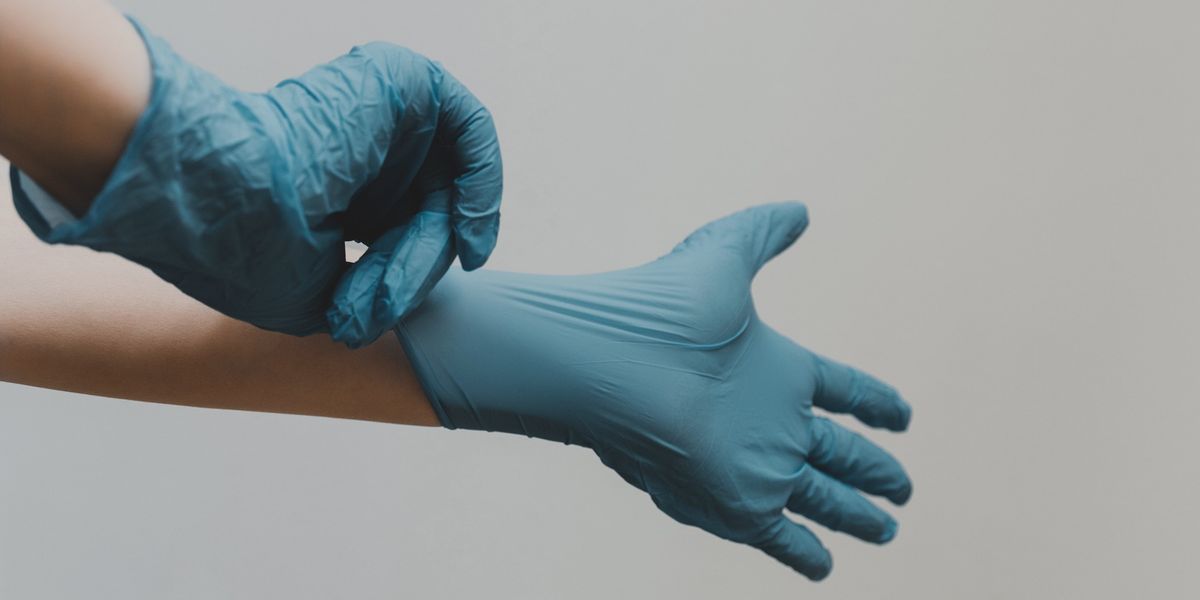 Person pulling on blue latex gloves