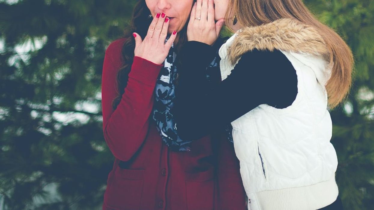 Woman whispering to another woman who is gasping