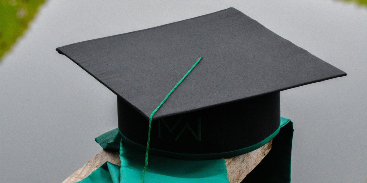 a graduation cap and a green tassel on a piece of wood