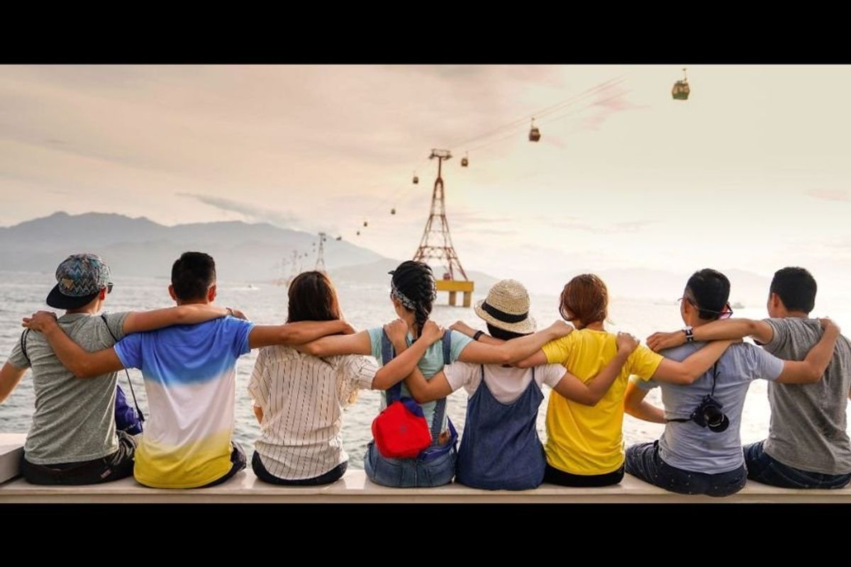 7 friends sitting arm in arm looking out over the water