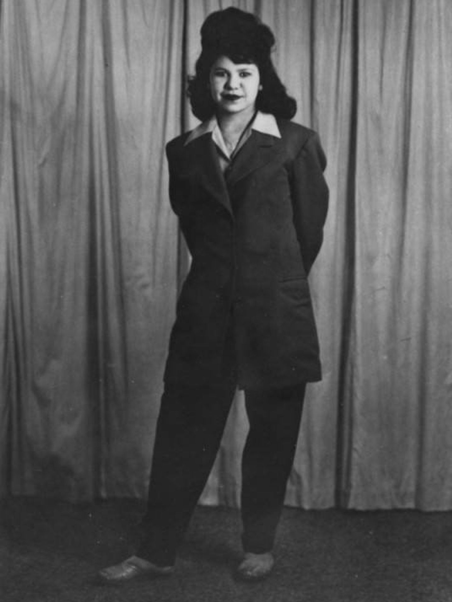 1944 black and white photograph of Ramona Fonseca, a young Mexican-American woman, posing confidently in a stylish zoot suit, representing the fashion and women of that era. The image is part of the historic Shades of L.A. Collection, highlighting the diverse families and communities in Los Angeles.