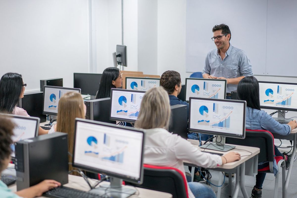 Teacher in a classroom teaching an IT class.
