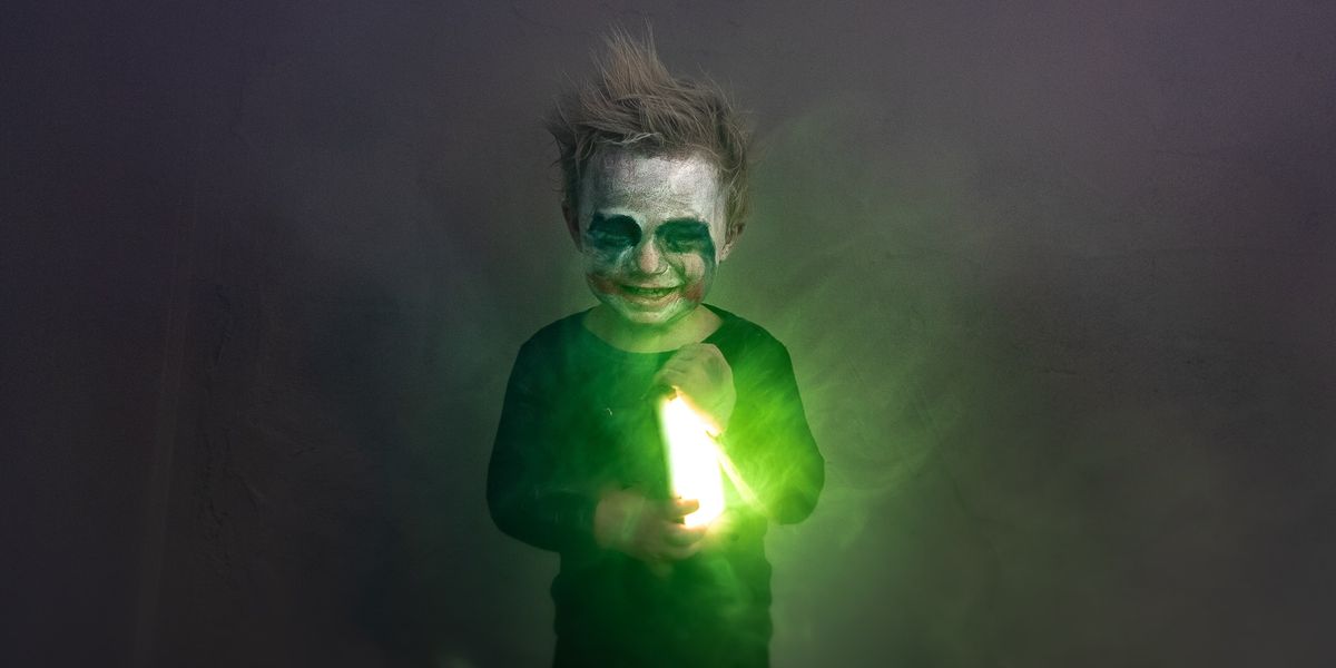 Child disguised as DC's Joker while holding an evil-looking green light