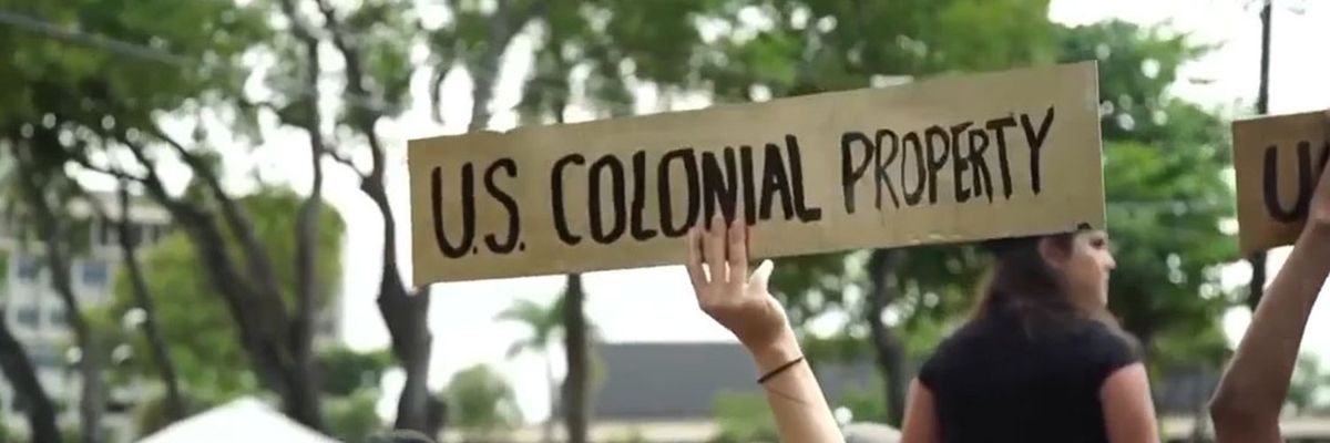 cardboard sign at a protest in puerto rico that reads "u.s. colonial property"