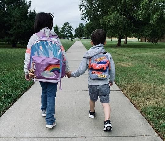Two children holding hands walking to school
