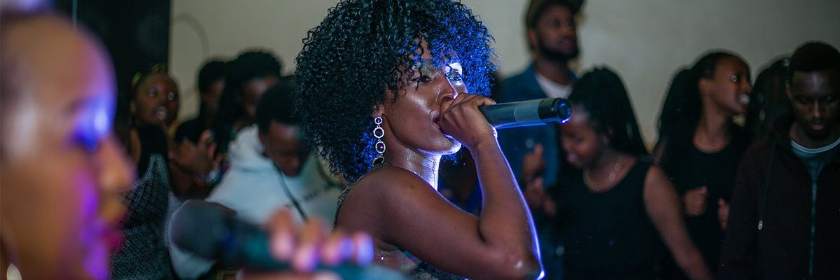 black woman with curly hair singing with a microphone