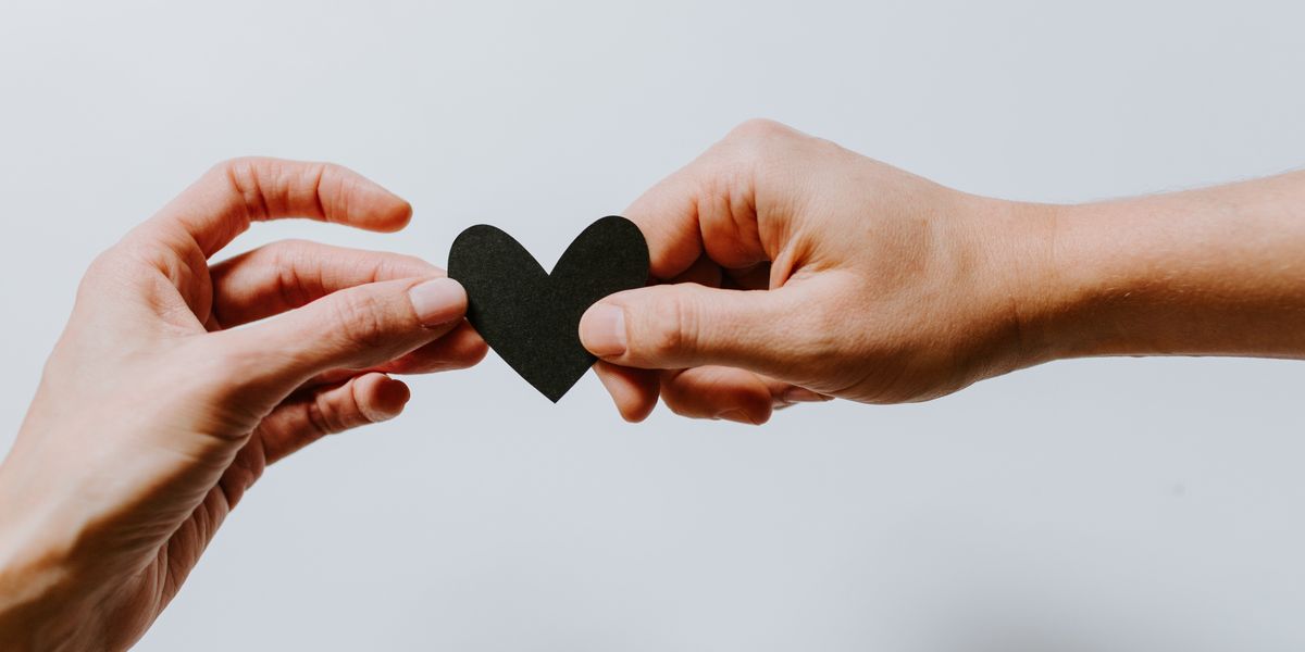 two people holding black paper heart