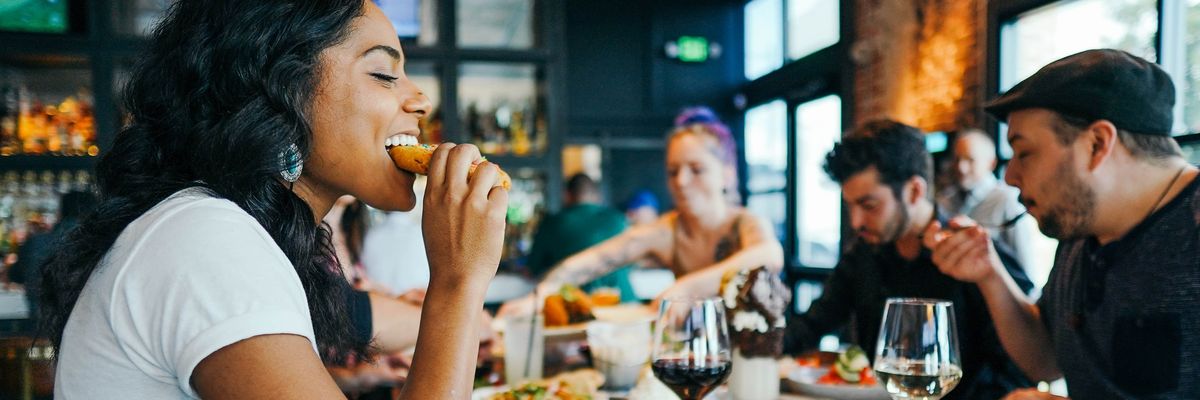 a woman eating bread at a table surrounded by other people at a restaurant