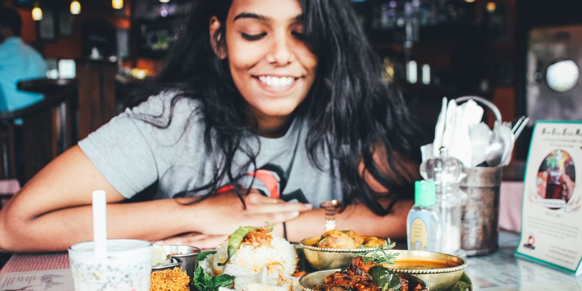 woman wearing grey shirt smiling while looking at a table full of food