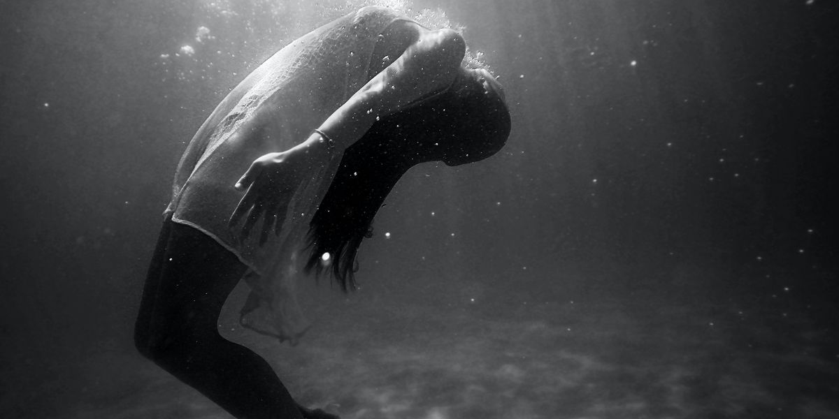 grayscale photo of woman drowning in water