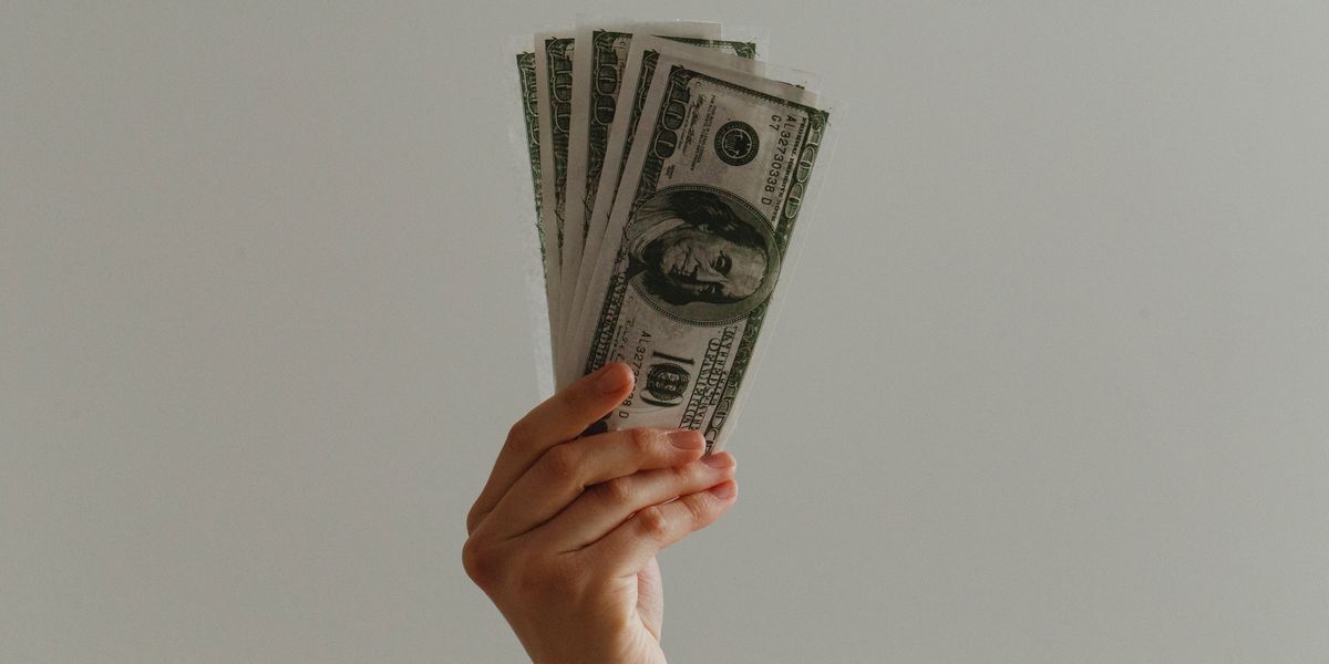 Person holding up multiple $100 U.S. dollar bills