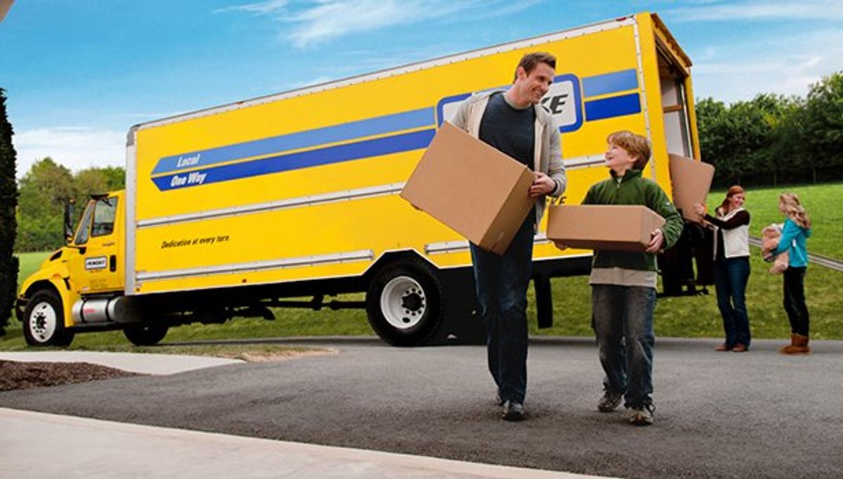 Family unloading boxes from a moving truck.