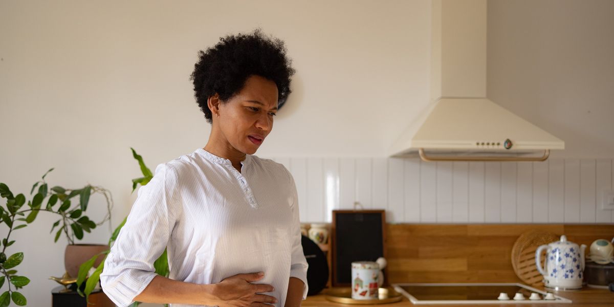 black-woman-holding-her-stomach-in-pain-at-home